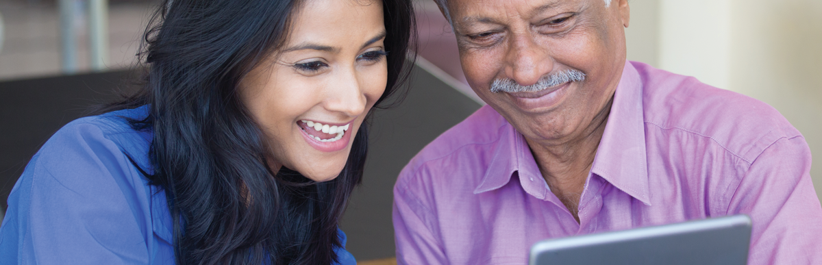 A woman showing an elderly man a digital tablet and smiling